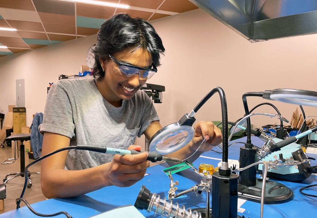 Meenaa Saththi, student assistant at Thode Makerspace, soldering an LED into a circuit board at Thode Makerspace can be seen.  