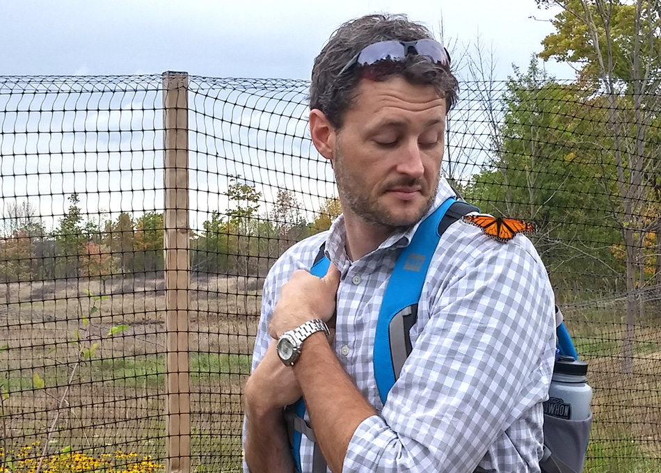 Chad Harvey looking at a butterfly on his shoulder can be seen.