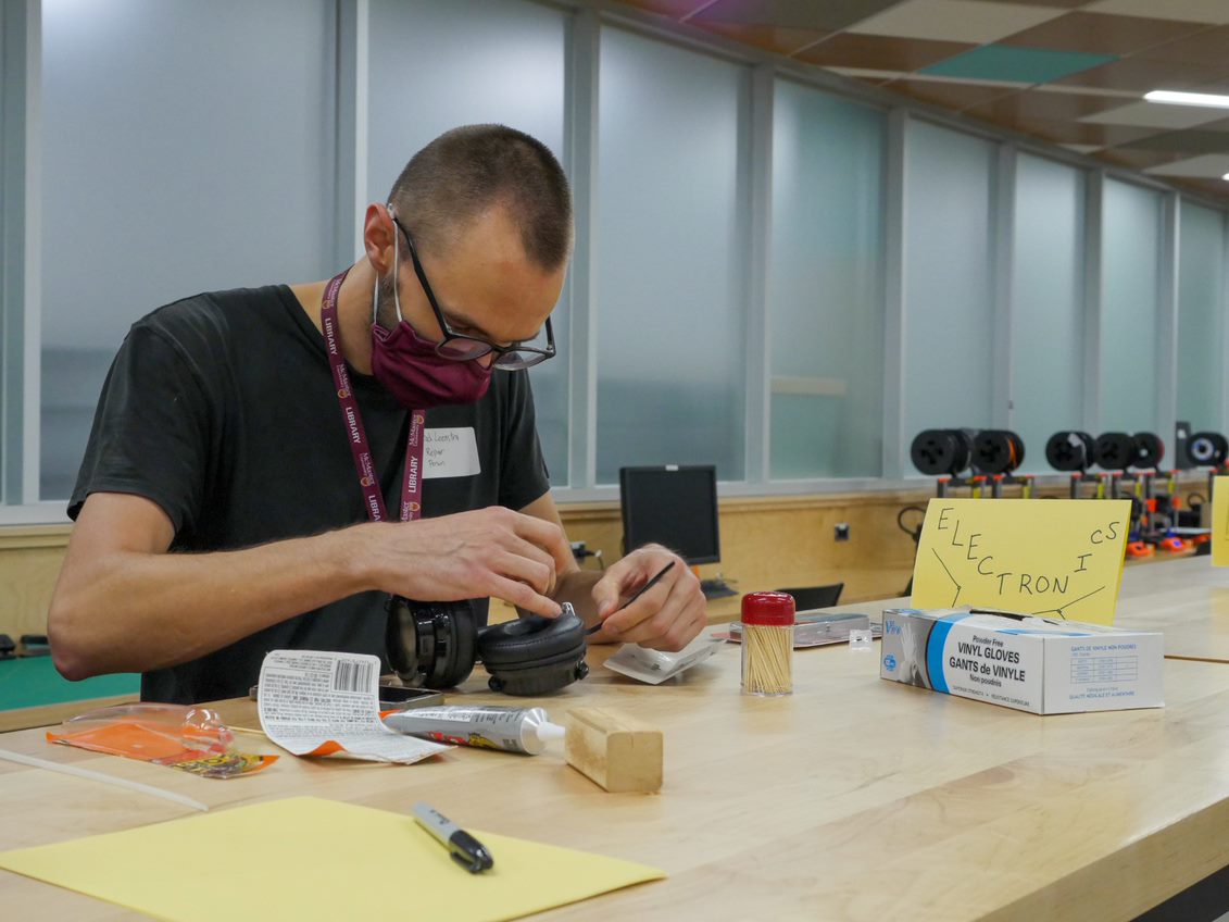 Brad Leenstra, repair volunteer and audio visual technologist with Campus Classroom Technologies at McMaster library, repairing headphones at the Thode Repair Cafe can be seen.