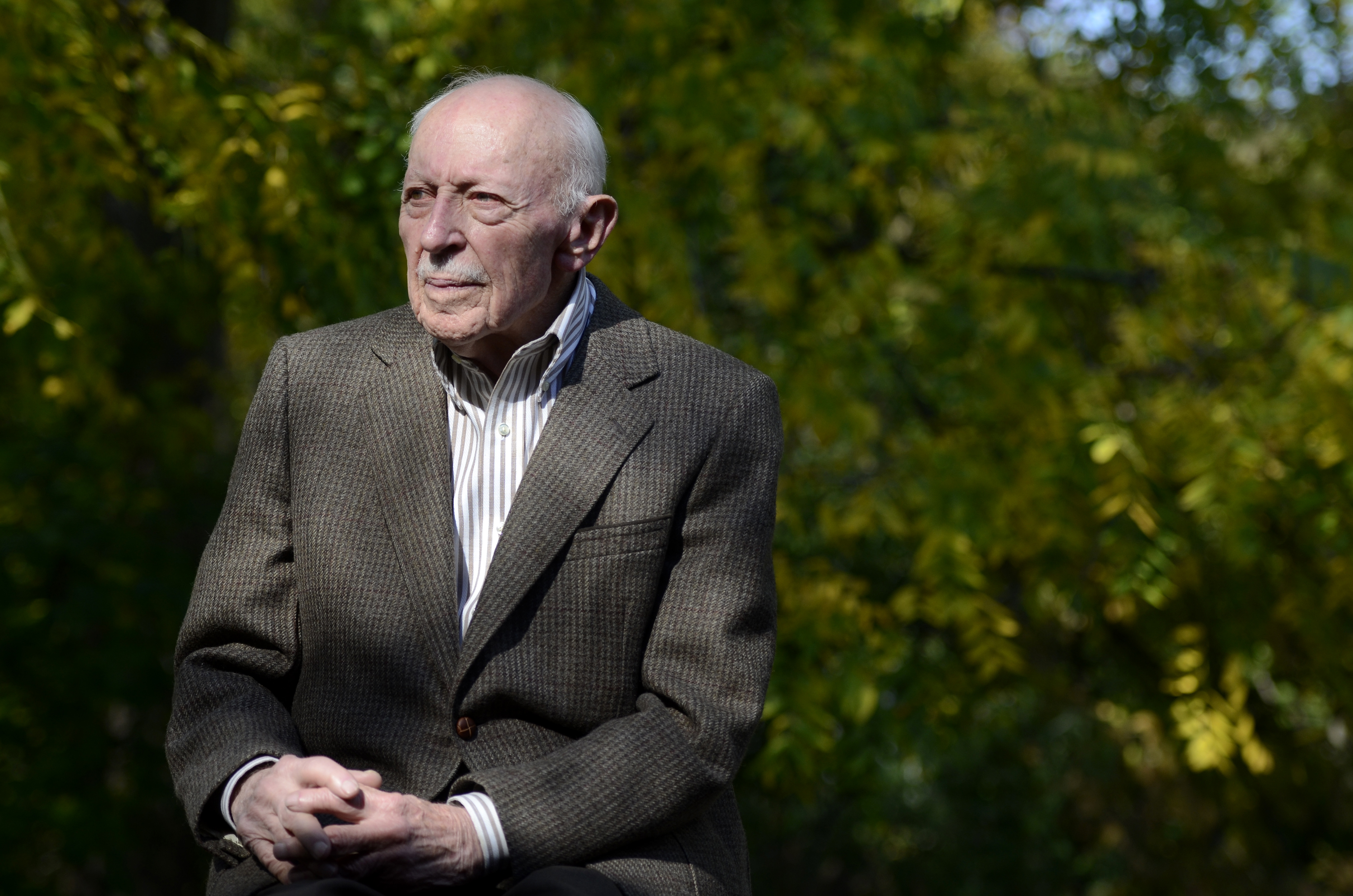 Rabbi Baskin, wearing a dark suit jacket and light dress shirt with a thoughtful expression, pictured outdoors on a sunny day.