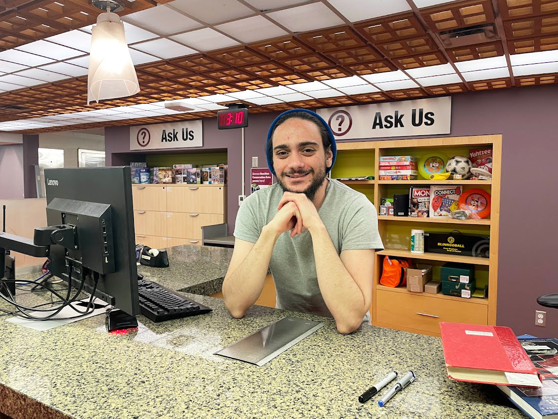 Ali Fikirkoca standing behind the service desk at Mills Library.