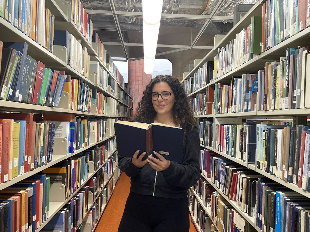 Jenna Owen, student assistant, stands among the bookshelves at H.G. Thode Library of Science and Engineering. 