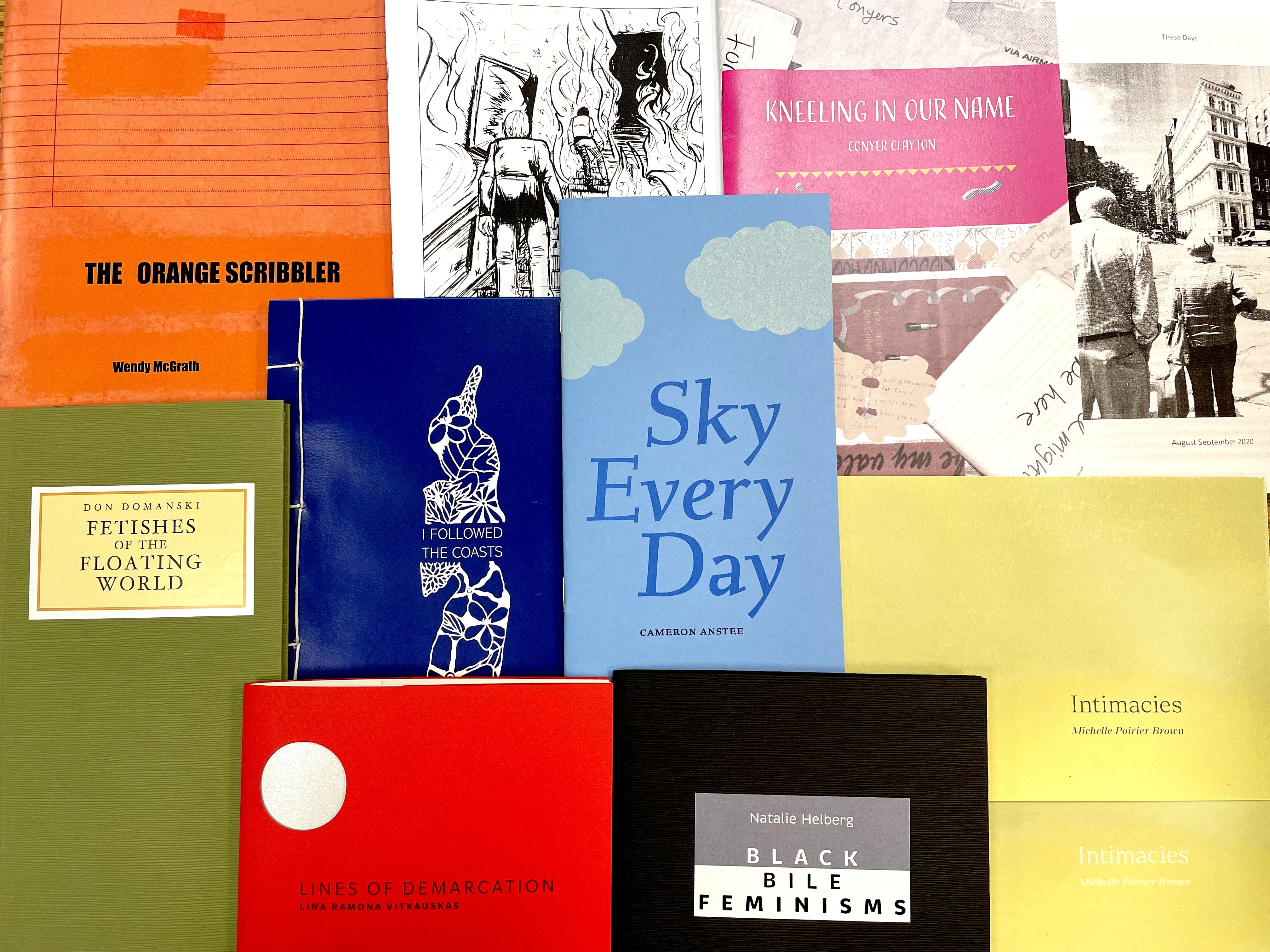 Various chapbooks with different coloured covers lay on top of one another.