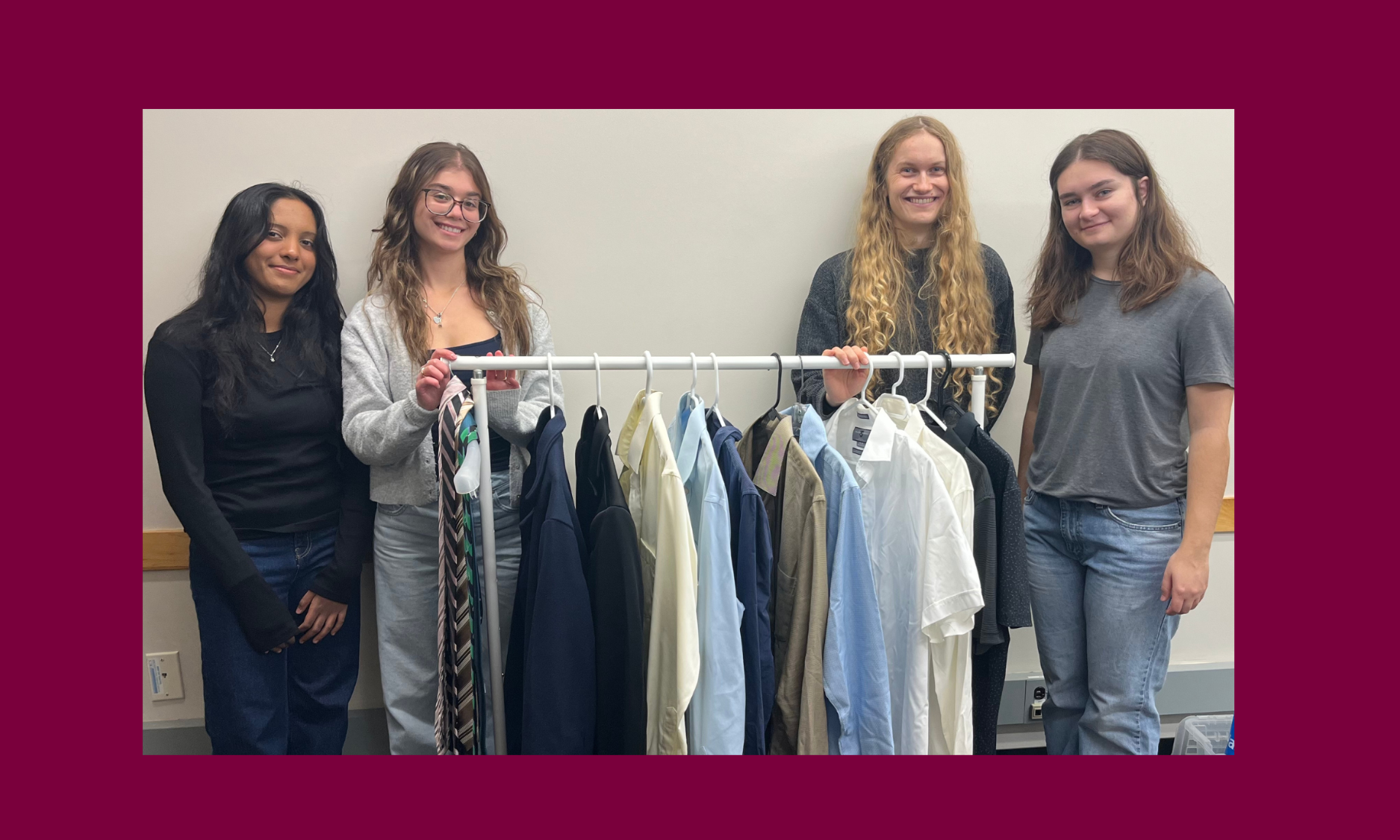 Four students stand with a clothing rack filled with dress shirts and blouses in different colours.