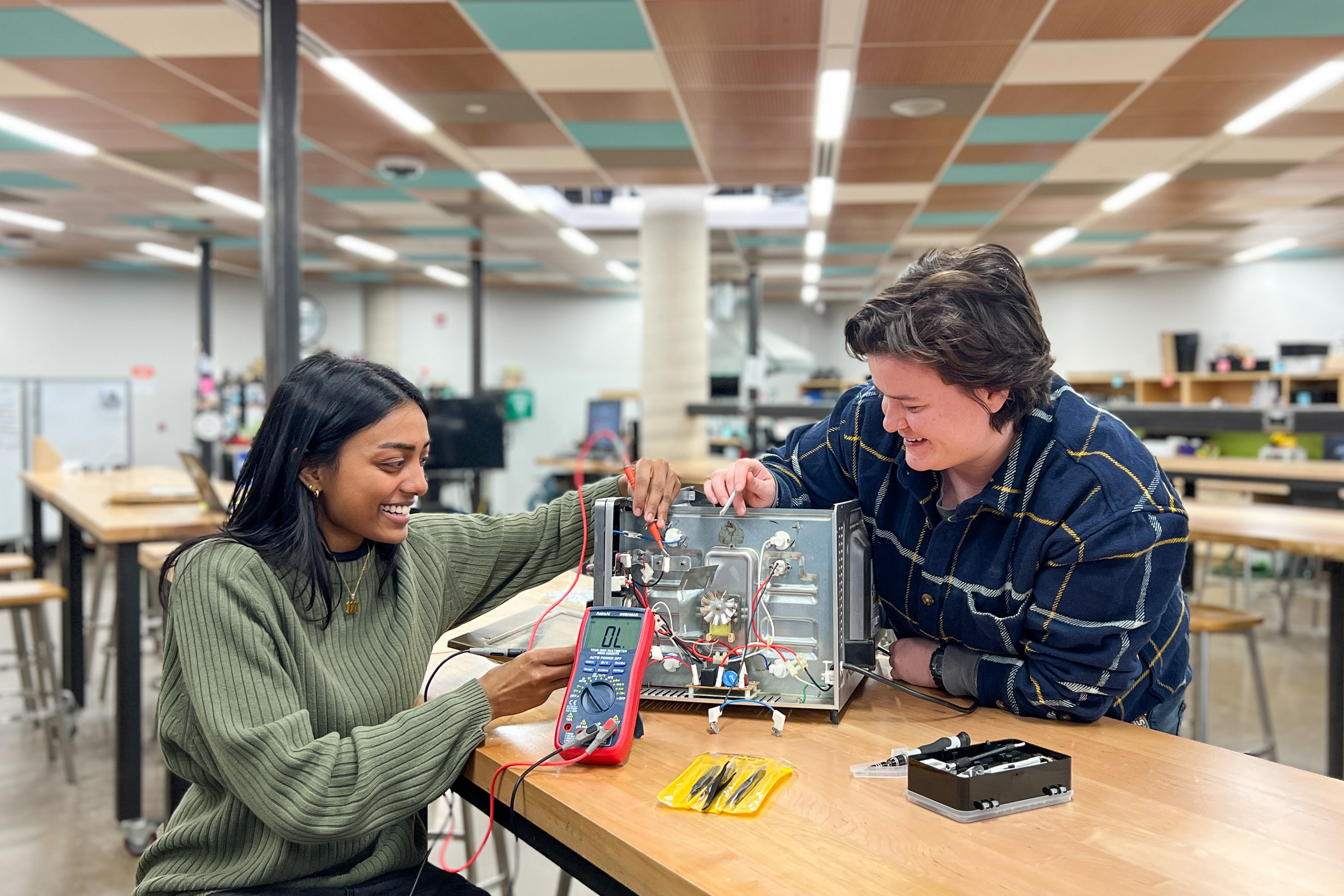 Meenaa Saththi, student assistant, left, and Britt Sostar, makerspace coordinator, right, fix a broken toaster oven in Thode Makerspace.
