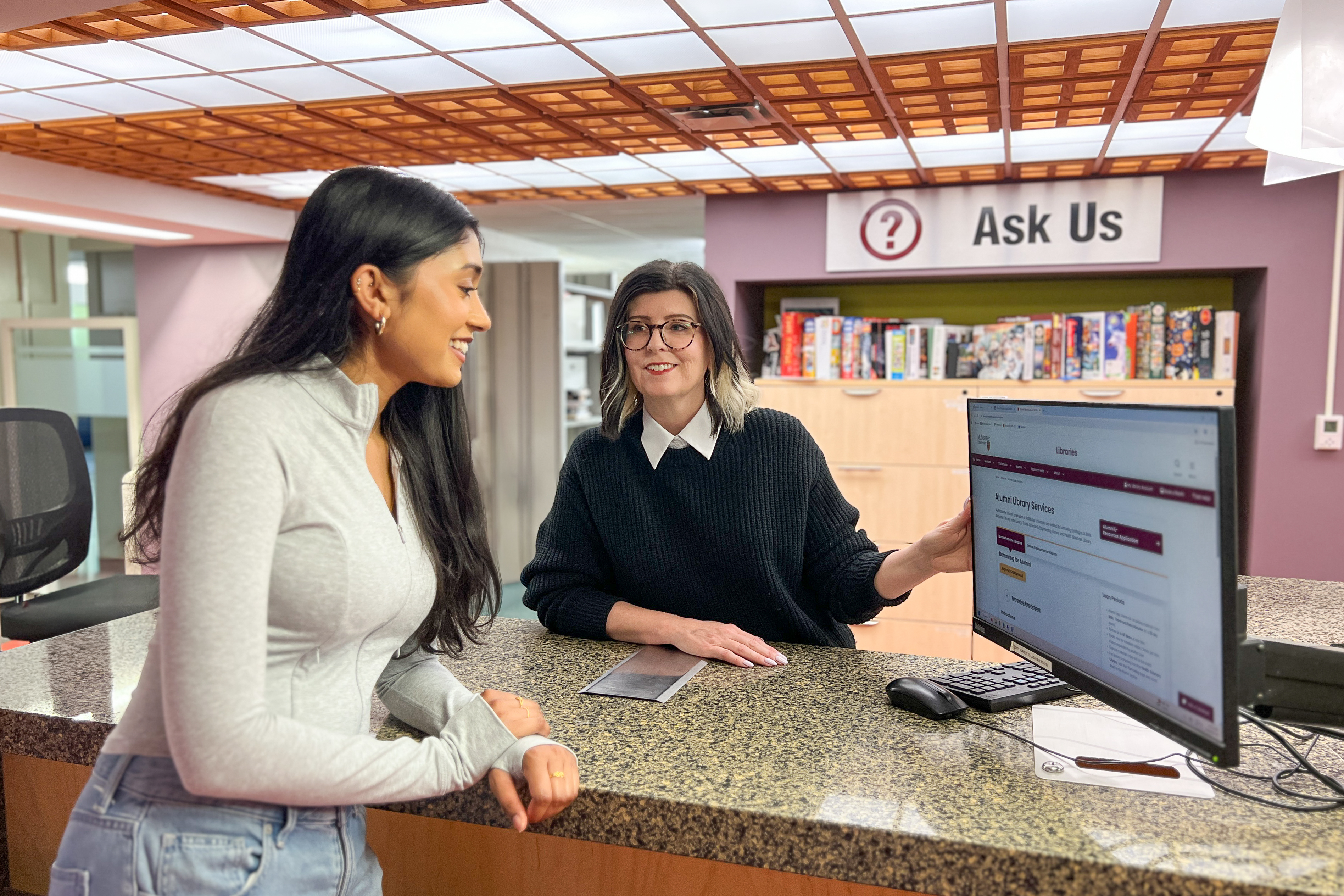 Student Krishah Kaileshan, left, and Crystal Mills, right, explore the Libraries’ alumni services webpage at the services desk in Mills Memorial Library.