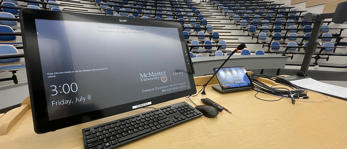 An example of presentation equipment available in Registrar-controlled classrooms. Pictured is a SMART digital annotation and touch screen monitor, a keyboard and mouse, podium gooseneck microphone, Crestron AV control touch panel, personal device connection cables and a document camera.  