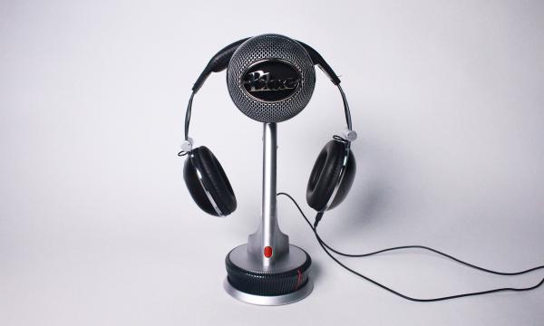 A Blue Snowball condenser microphone with headphones balanced on top.