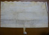 Handwritten vellum document with seal tag at bottom and scalloped top edge