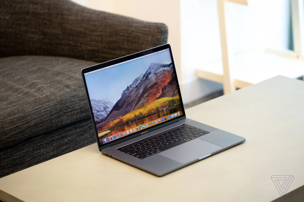 An open 15-inch MacBook Pro (2018) showing a wallpaper of mountains and a body of water
